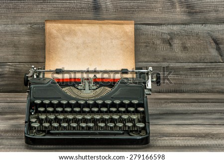 Antique typewriter with old textured paper page on wooden table. Vintage style toned picture