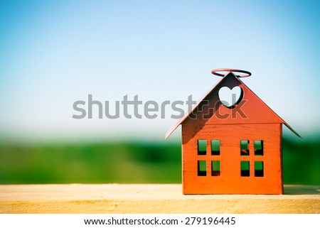 red model of house as symbol on nature background