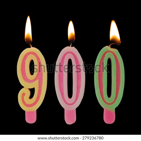 Burning birthday candles on black background, number 900