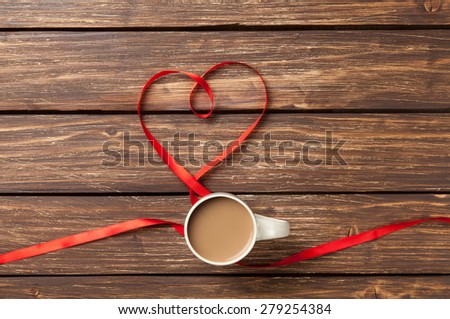 Cup of coffee and bow in heart shape symbol on wooden table