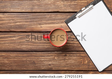 Cup of coffee latte and business tablet with paper on wooden table.