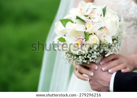 Betrothed pair holding a delicate bouquet of roses and orchid outdoor in pastel colours on green holiday background copyspace, horizontal picture