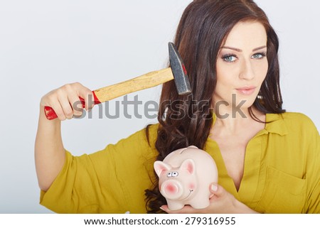 young woman smashed piggy bank with a hammer in a studio