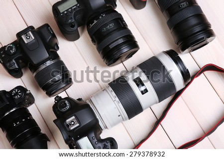 Modern cameras on wooden table, closeup
