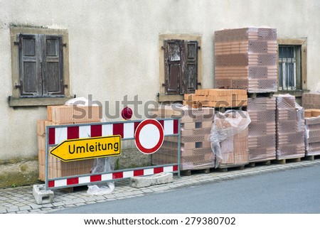 german diversion sign "Umleitung" in front of an old building and stacks of bricks