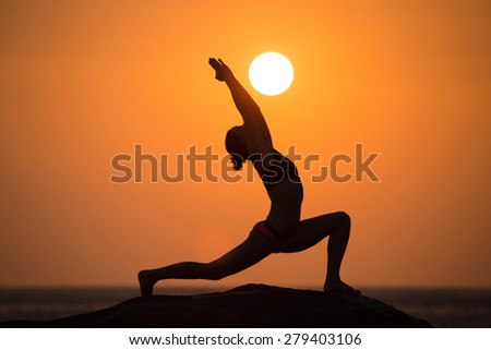 Warrior pose from yoga by woman silhouette on sunset Royalty-Free Stock Photo #279403106