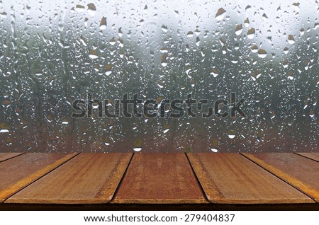 Rain Drops on Glass Window Background with Wood Table.