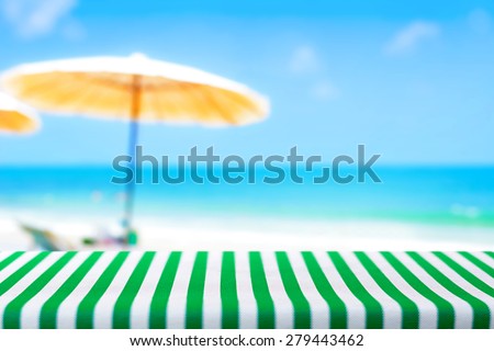 Table covered with striped tablecloth on blurred beach background - picnic and holiday concepts