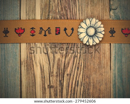 vintage band with embroidered ornaments andÃ?Â old button on a textured surface aged boards. instagram image filter retro style