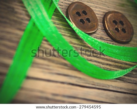 still life with old green tape and two vintage buttons on a textured surface aged boards. instagram image filter retro style