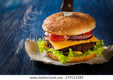 Hamburger pinned with knife on paper