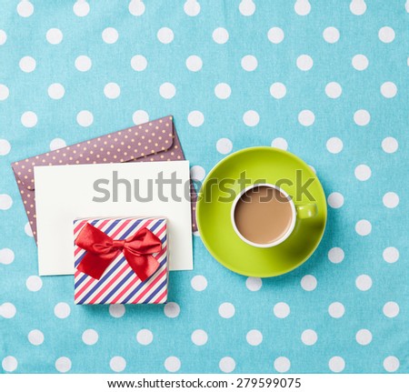 Cup of coffee and envelope with gift boxes on blue polka dot background 