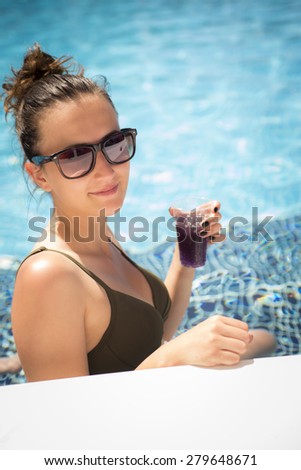 Young woman in the swimming pool with a cocktail.