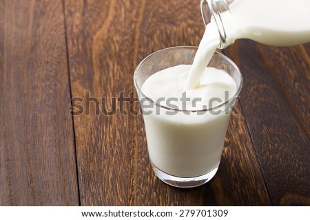Pouring milk  into glass Royalty-Free Stock Photo #279701309
