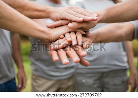 Happy volunteer family putting their hands together on a sunny day Royalty-Free Stock Photo #279709709