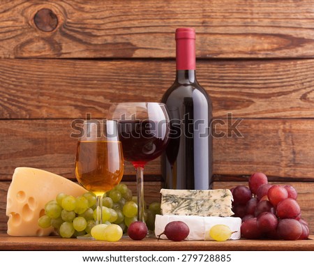 ?heese, grapes and wine bottles on wooden table in restaurant