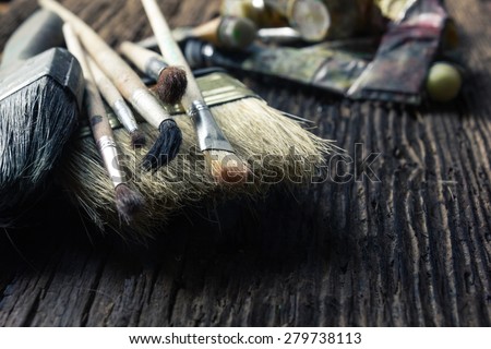 Artist paintbrushes close up on old natural rustic grunge wooden shabby desk background. Toned picture