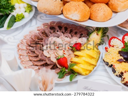 Buffet table served with tasty meals. Assorted meat, stuffed chicken roll, ham with mushrooms and greens decorated with fruit