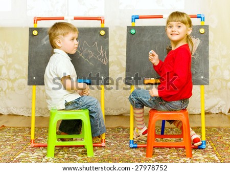 girl and boy drawing on the blackboard with chalk