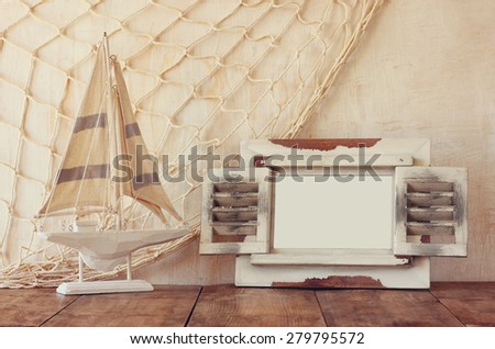 old vintage wooden white frame and sailing boat on wooden table. vintage filtered image. nautical lifestyle concept
