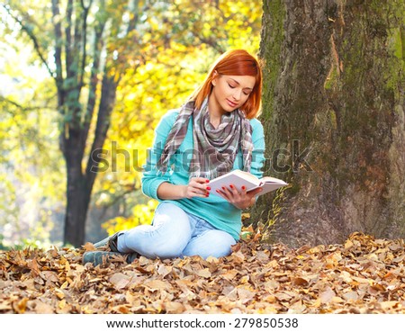 Young woman reading a book in park.