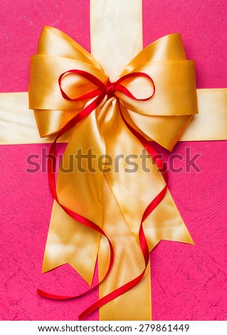 golden bow made from silk on pink background