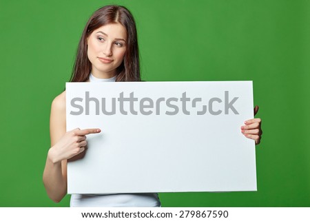 Beautiful woman gesticulating, holding white blank advertising board banner, on green background