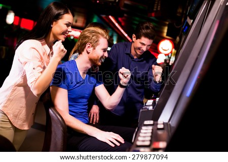 Young people at slot machine in the casino Royalty-Free Stock Photo #279877094