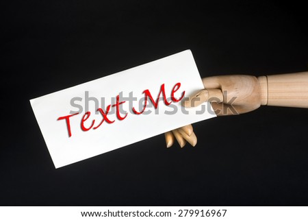 Text me sign held by funny wooden hand.