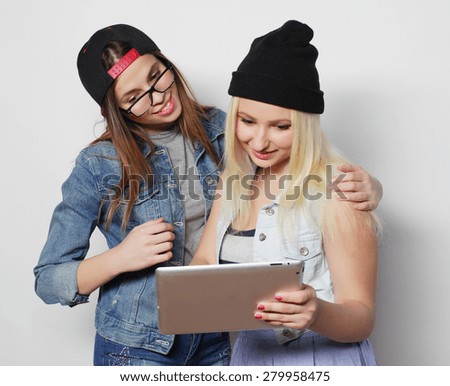 Two pretty hipster girls taking a self portrait with a tablet, over white background, not isolated