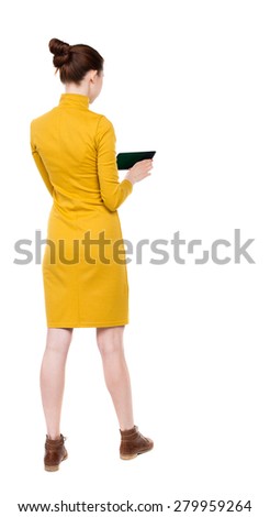 back view of standing young beautiful  girl with tablet computer in the hands of. girl  watching. Rear view people collection.  backside view of person.  Isolated over white background.