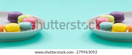 Two dishes of colourful french macaron on green background 