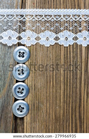 vintage button and lace tape on old wooden surface