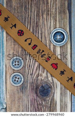 vintage band with embroidered ornaments andÂ old buttons on a textured surface aged boards