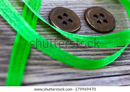 still life with old green tape and two vintage buttons on a textured surface aged boards