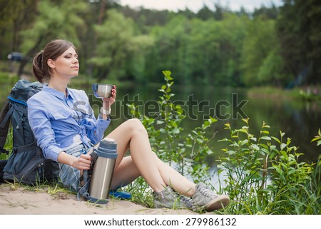 Hiker with backpack relaxing by the lake in a forest and enjoying view of Forest