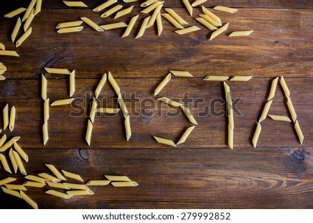pasta sign made of penne pasta on dark wood rustic table background overhead angle shot