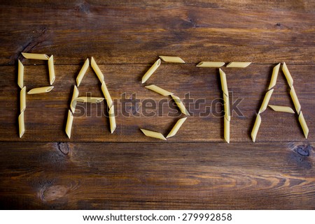 pasta sign made of penne pasta on dark wood rustic table background overhead angle shot