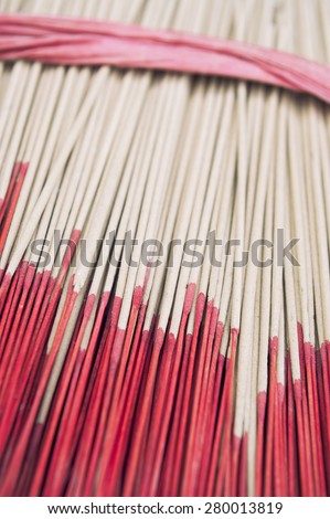 Bundle of red-tipped sticks of incense in wrapped in simple ribbon in a Buddhist shrine in Bangkok, Thailand