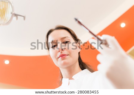 Serious female dentist holding a syringe in hand . Patient's view. Focus on the woman
