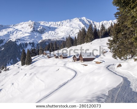 Foisch, Switzerland: Snowy mountain chalet in wood and illuminated by the sun create a aplendido winter scenery and characteristic of the Swiss Alps. Royalty-Free Stock Photo #280120073