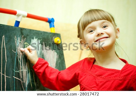 Girl draws with chalk on the blackboard