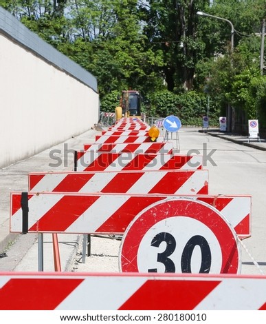 speed limit sign and hurdles in the road excavation for the laying of optical fibre
