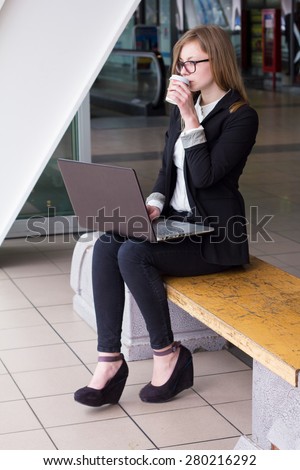 Young business woman with a laptop drinking coffee