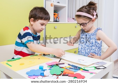 Two preschool child create a picture with foam shapes