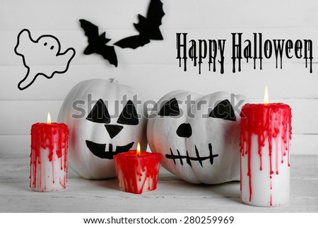 White Halloween pumpkins, candles on white wooden background