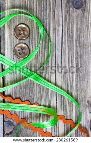 still life with old green and red tapes and two vintage buttons on a textured surface aged boards