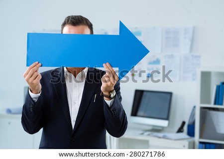 Businessman holding a big arrow pointing to the right