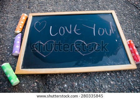 I love you message with hearts on chalkboard with colorful street chalk