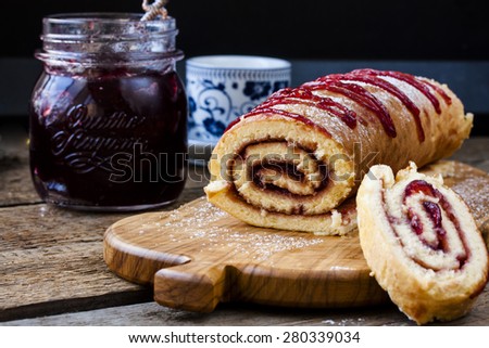 Biscuit roulade with cherry jam on a background of wooden boards Royalty-Free Stock Photo #280339034